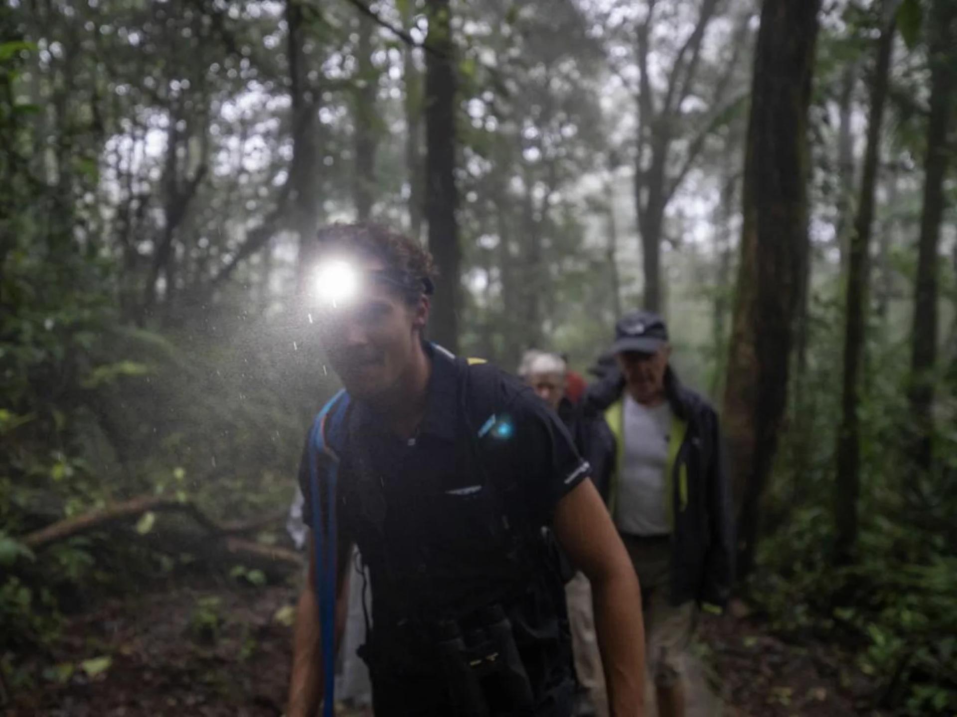 Lucas Boyat guidant à la lampe torche des voyageurs dans la forêt nuageuse de Monteverde