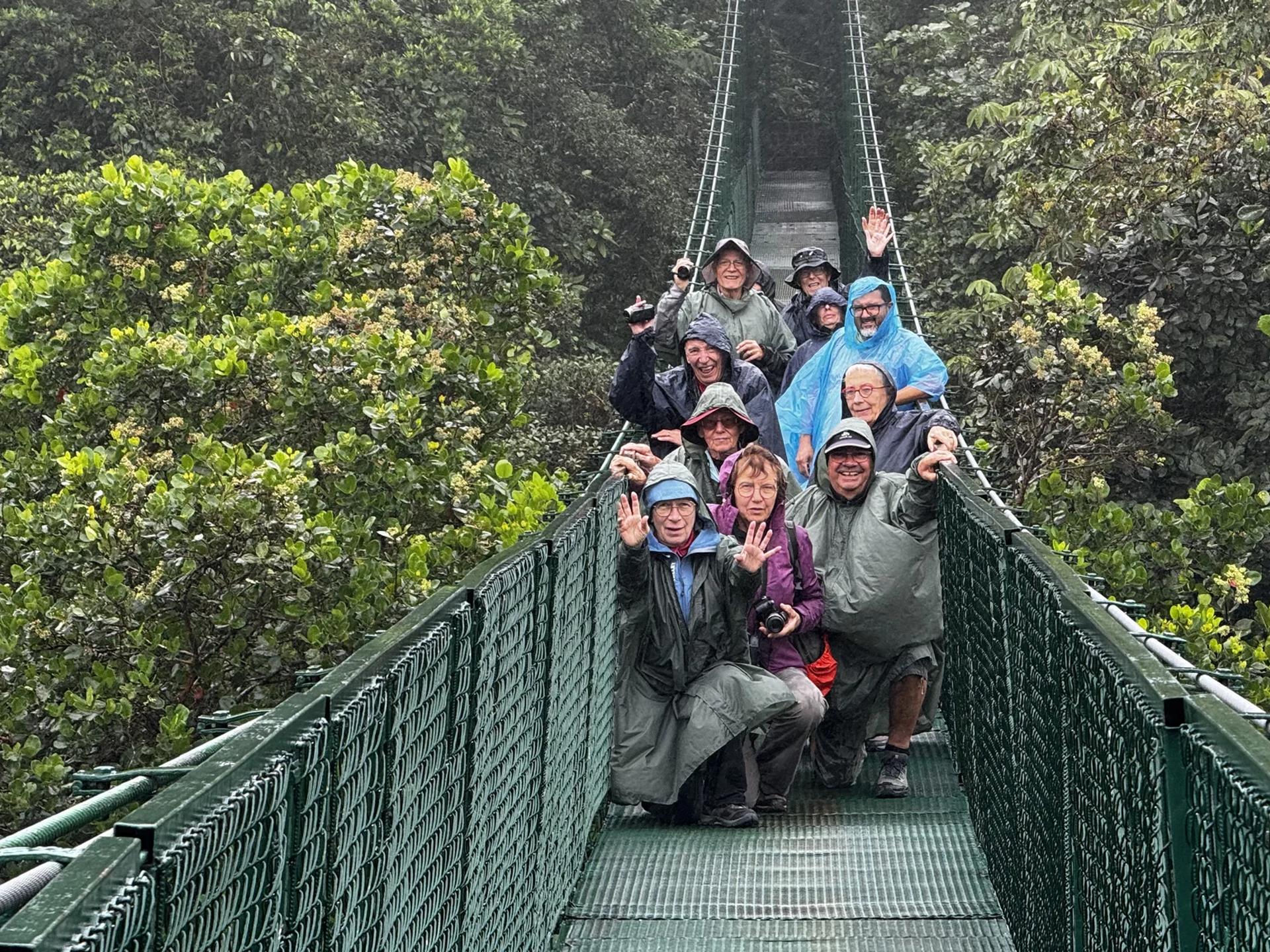 Groupe de voyageurs heureux pour une photo sur un pont suspendu au coeur de la foret nuageuse du costa rica