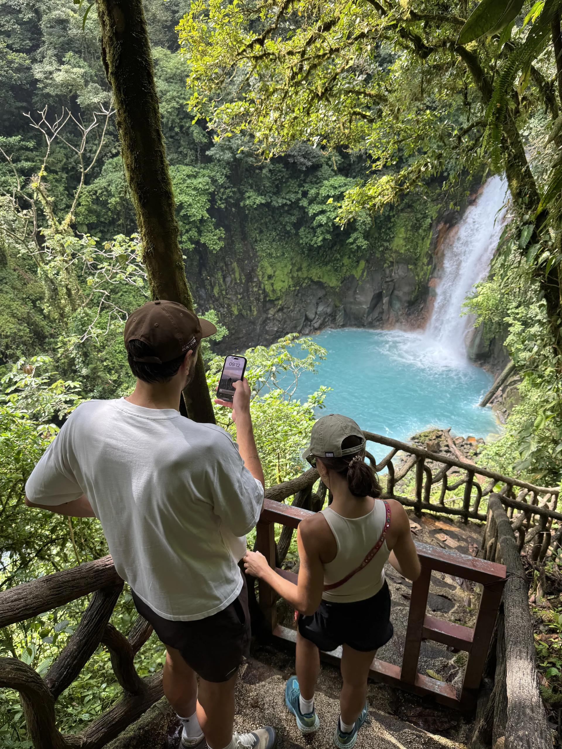 Vue sur la cascade du Rio Celeste dans le parc national Tenorio avec un couple de dos qui descend les marches