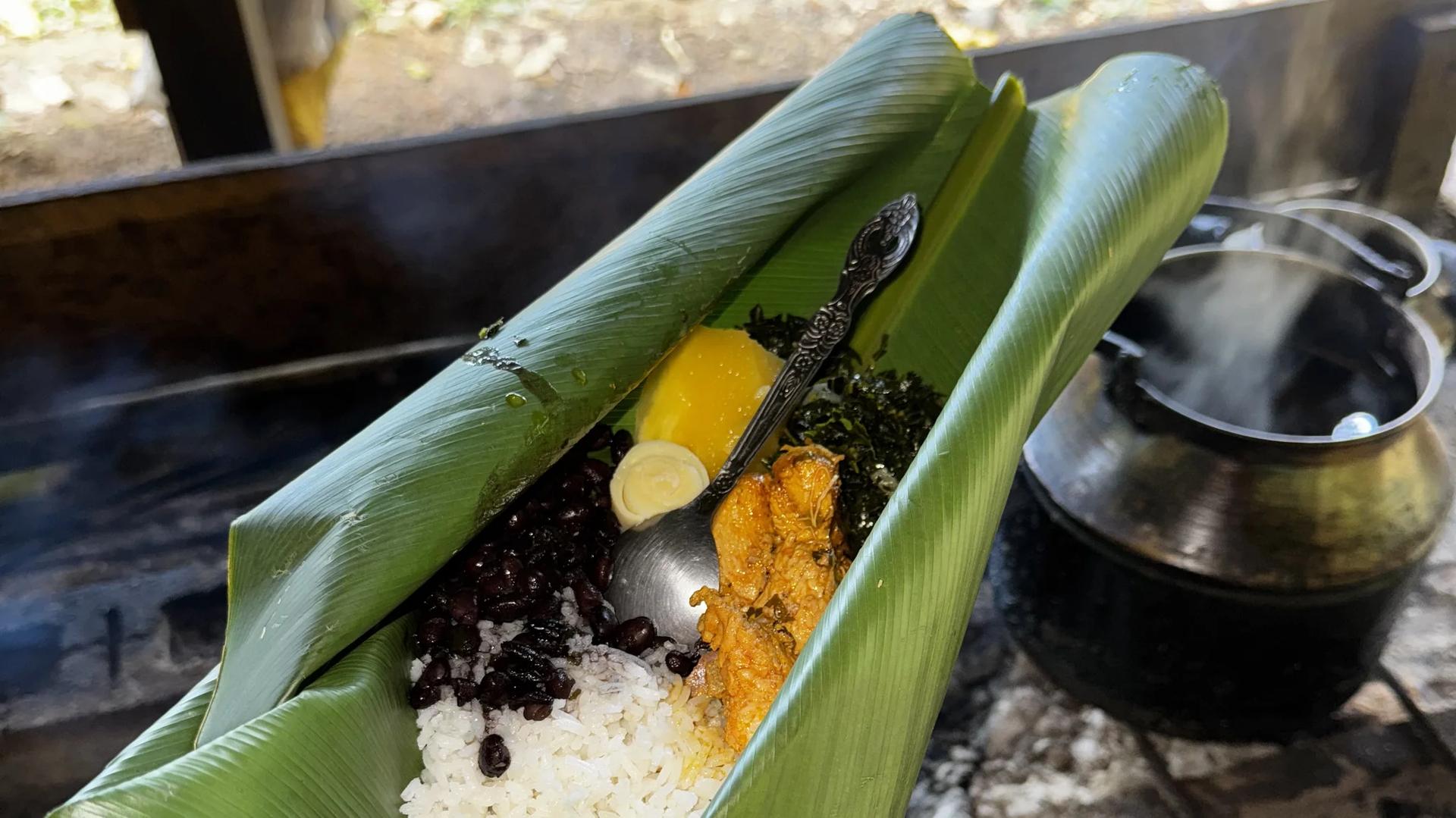 Déjeuner typique bribri avec riz, poulet, haricots noirs et manioc servis dans une feuille de bananier