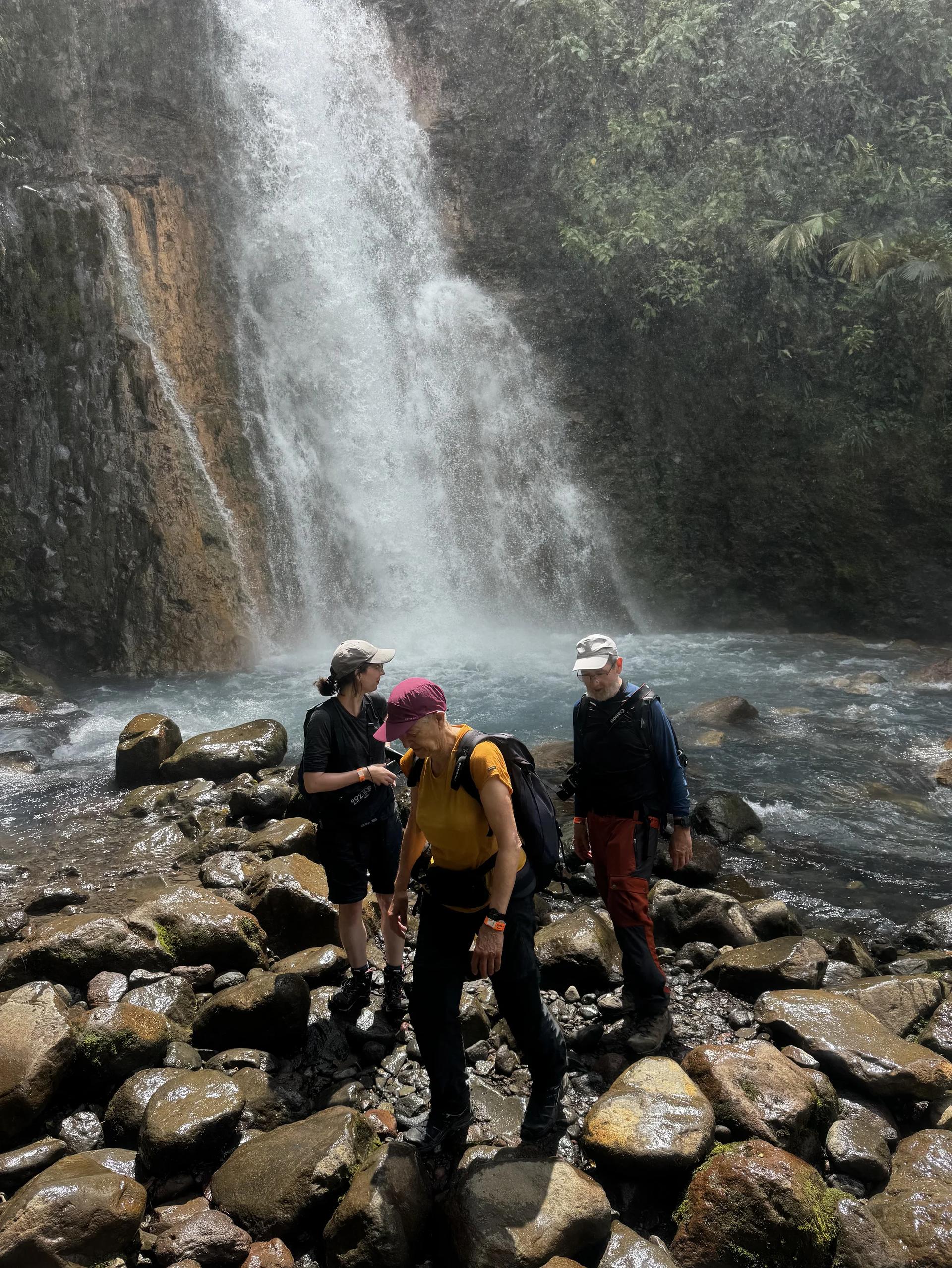 3 voyageurs marchant devant une cascade à Bajos del Toro