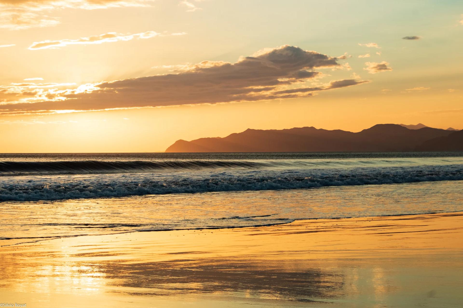 Soleil caché derrière des nuages au dessus de vagues en formation sur la plage Naranjo, Parc National Santa Rosa