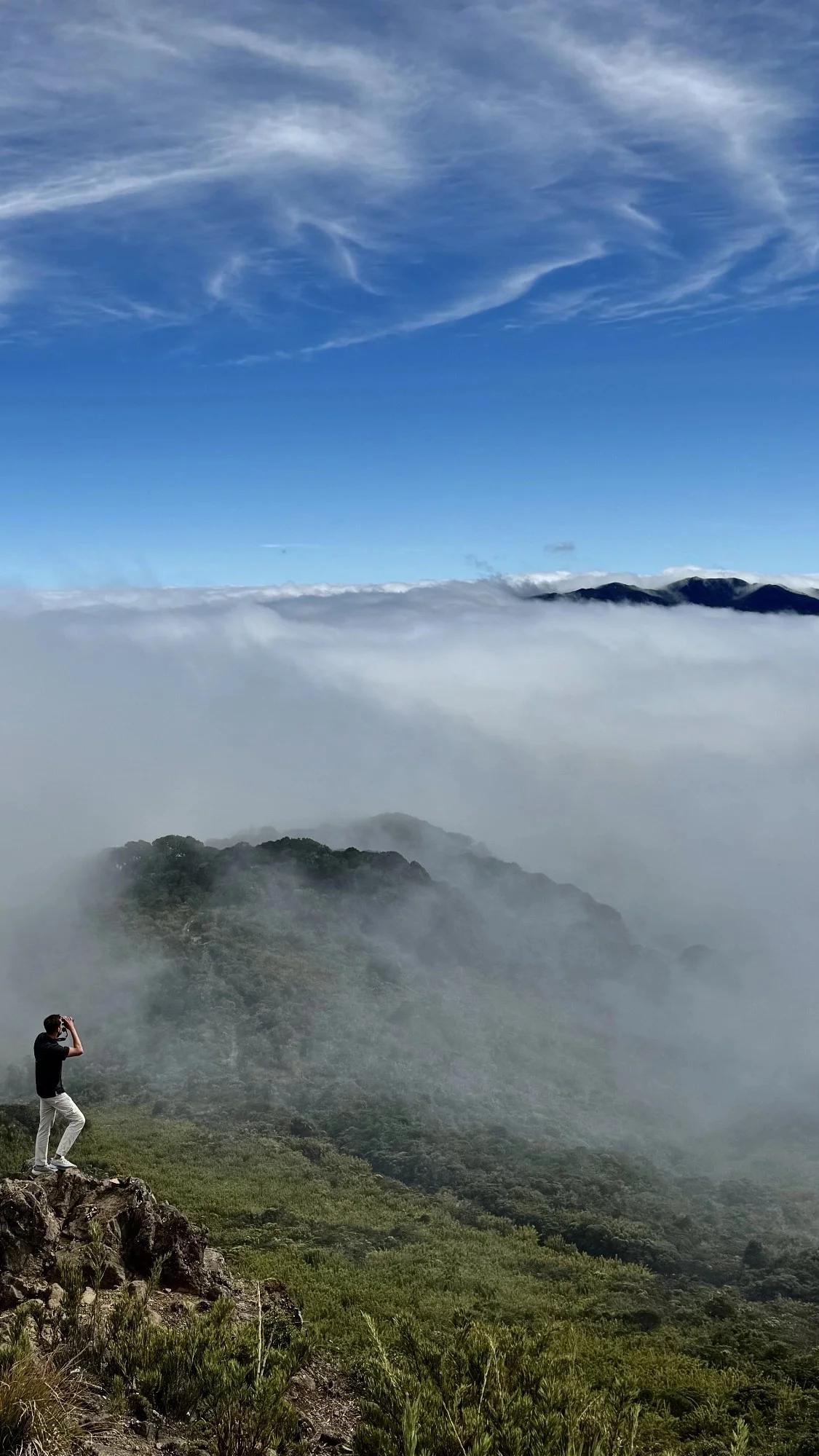 Lucas Boyat admirant avec jumelles la mer de nuages et le volcan irazu